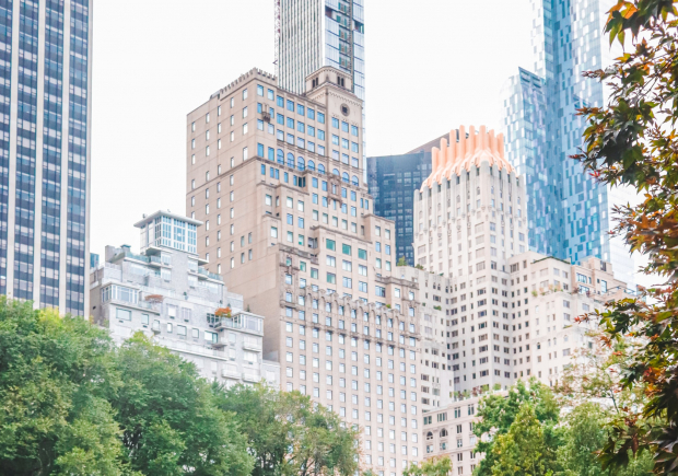 photo of a woman in Central Park with trees and tall buildings in the background