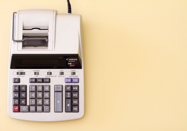 A photo of an accounting calculator on a solid pale yellow background