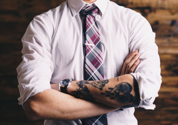 Photo of man with folded arms and tattoos