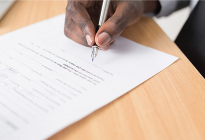 photo of a hand signing a document